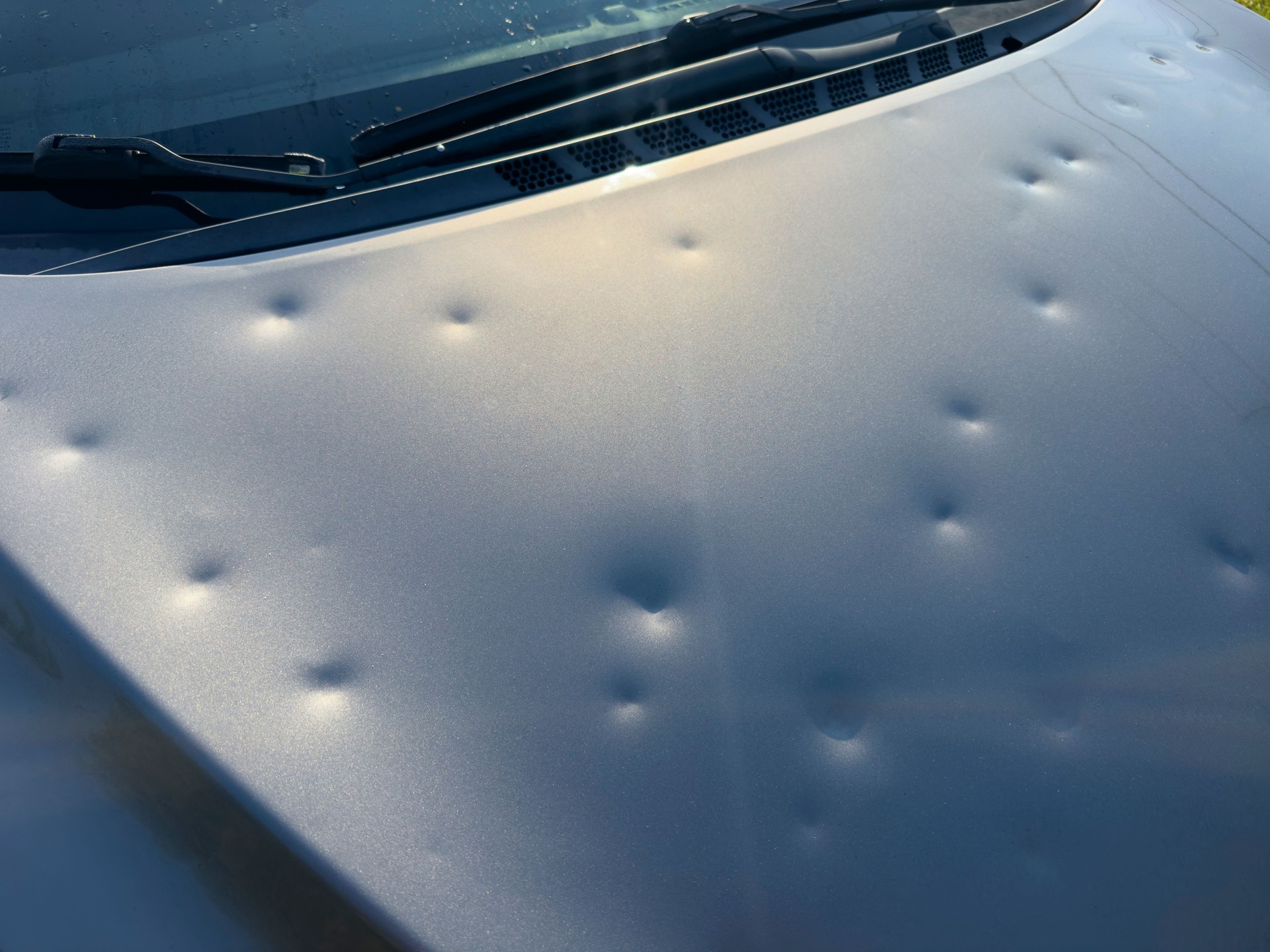 Car hood covered in hail damage dents.